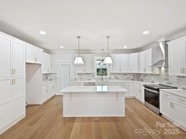 kitchen featuring a kitchen island, stainless steel appliances, light wood-type flooring, wall chimney range hood, and white cabinetry