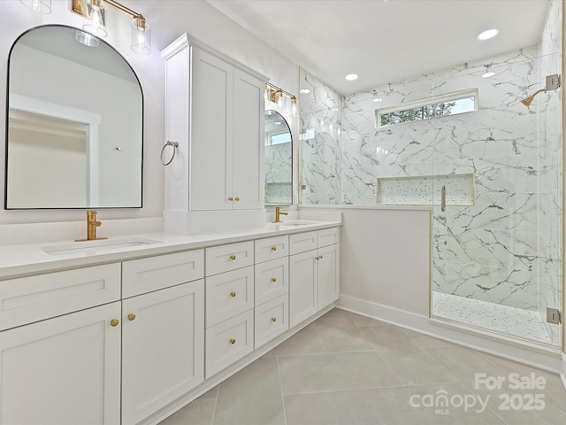 bathroom with double vanity, tile patterned flooring, a sink, and a marble finish shower