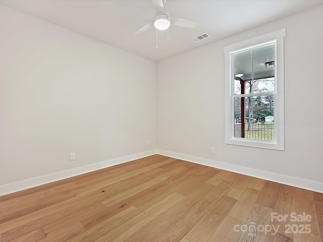 empty room featuring light wood-type flooring, baseboards, visible vents, and a ceiling fan