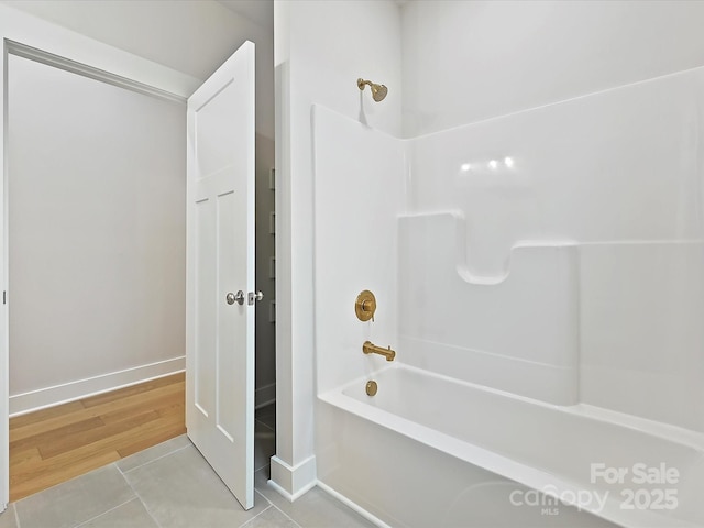 bathroom featuring wood finished floors, shower / tub combination, and baseboards