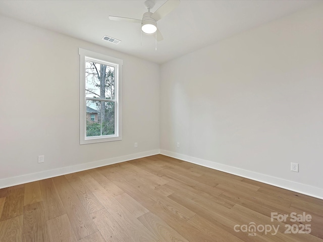 empty room featuring baseboards, visible vents, ceiling fan, and wood finished floors