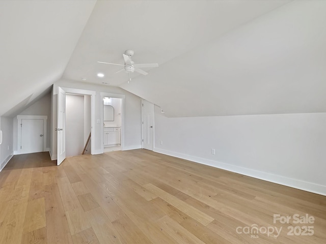 additional living space with vaulted ceiling, baseboards, a ceiling fan, and light wood-style floors