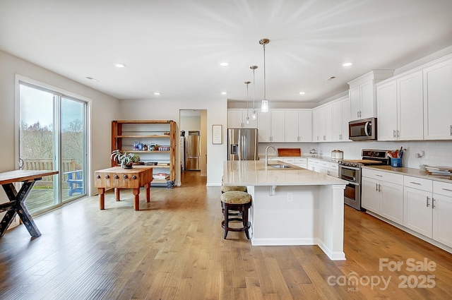 kitchen with white cabinetry, light wood-type flooring, appliances with stainless steel finishes, and a sink