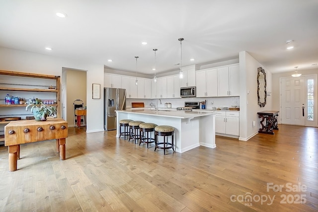 kitchen with stainless steel appliances, a kitchen bar, light wood-style floors, and light countertops