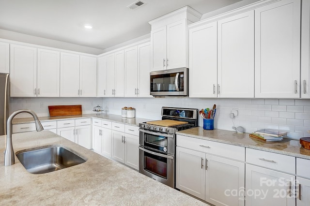 kitchen with tasteful backsplash, visible vents, appliances with stainless steel finishes, and a sink