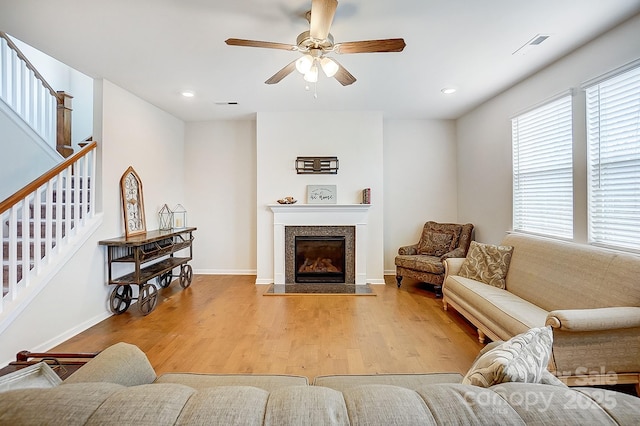 living room with visible vents, wood finished floors, stairway, a premium fireplace, and baseboards