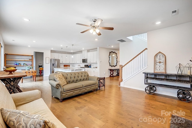 living room featuring light wood-type flooring, visible vents, recessed lighting, stairway, and ceiling fan