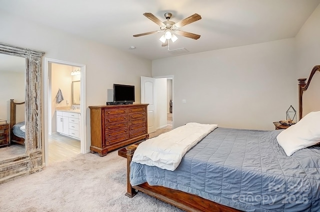 bedroom with light colored carpet, connected bathroom, and a ceiling fan