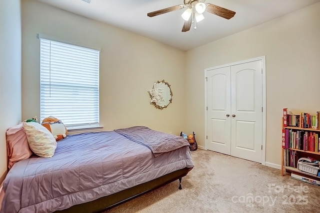 bedroom with light carpet, baseboards, a closet, and a ceiling fan