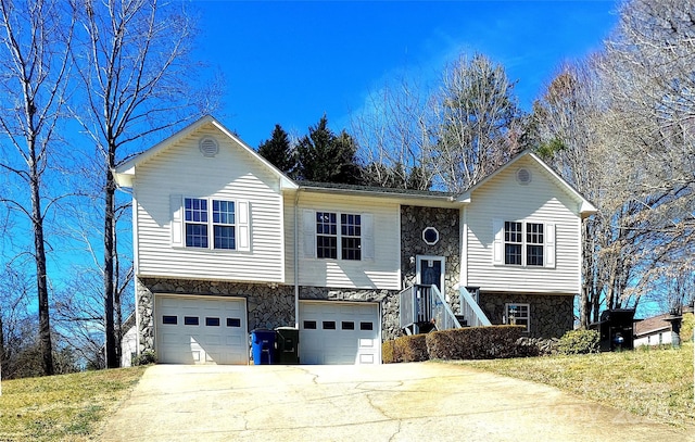 split foyer home with driveway, stone siding, and a garage