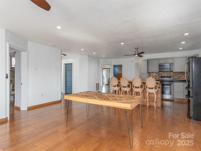 dining space with visible vents, a textured ceiling, wood finished floors, and a ceiling fan