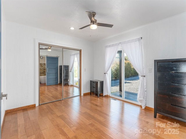 unfurnished bedroom featuring baseboards, light wood-type flooring, a ceiling fan, and access to exterior