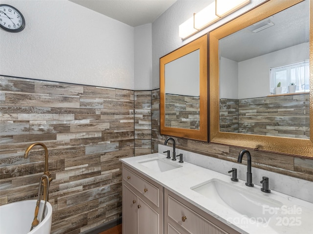 bathroom featuring double vanity, wood walls, a freestanding bath, and a sink