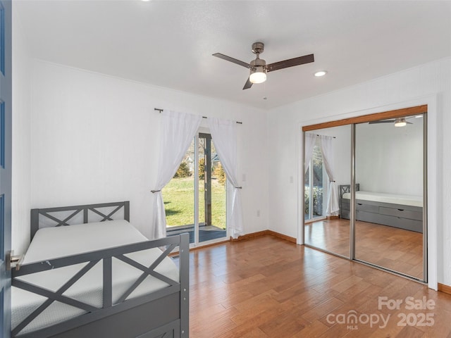 unfurnished bedroom featuring wood finished floors, a ceiling fan, baseboards, access to outside, and a closet