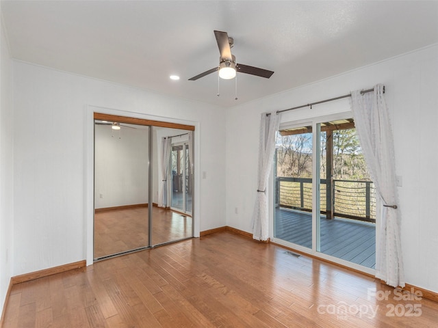 unfurnished bedroom featuring access to exterior, a closet, visible vents, wood finished floors, and baseboards