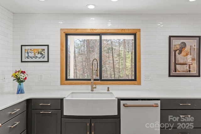 kitchen with light countertops, a sink, backsplash, and dishwasher