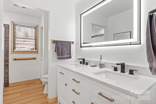 full bathroom with toilet, wood finished floors, a sink, and visible vents