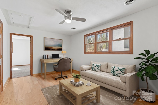 living area with light wood-style flooring, a ceiling fan, visible vents, and baseboards