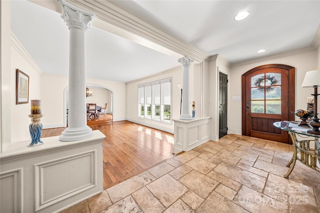 foyer entrance featuring arched walkways, stone tile floors, recessed lighting, ornamental molding, and ornate columns