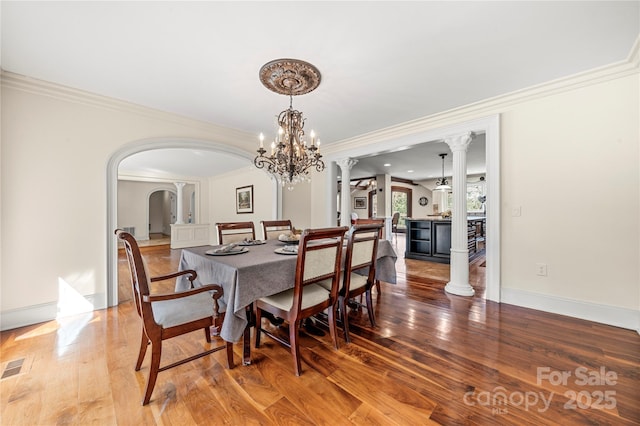 dining area featuring ornamental molding, decorative columns, baseboards, and wood finished floors