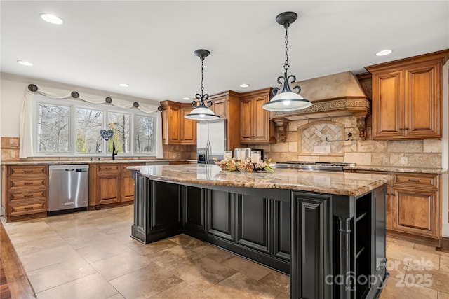 kitchen featuring brown cabinetry, custom range hood, a center island, light stone countertops, and stainless steel appliances