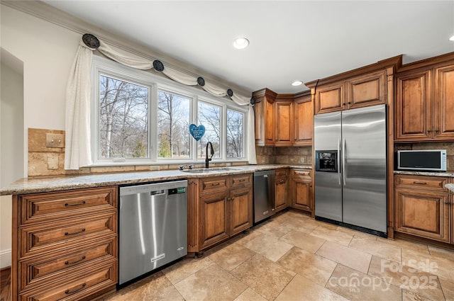 kitchen featuring tasteful backsplash, appliances with stainless steel finishes, a sink, and brown cabinets