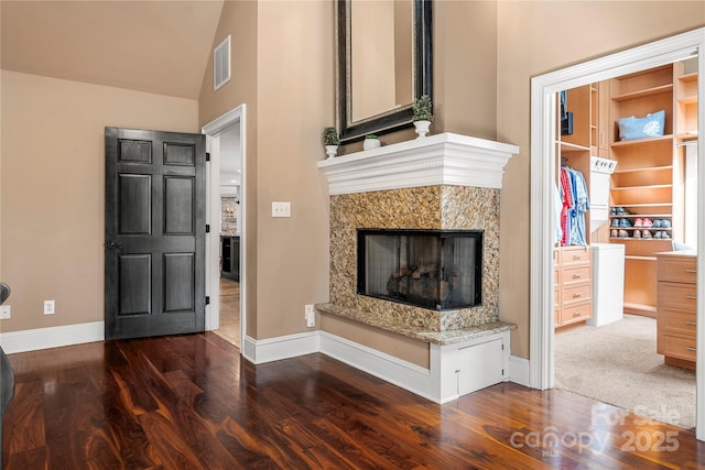 interior space featuring visible vents, a premium fireplace, baseboards, and wood finished floors