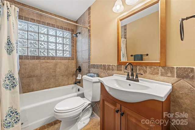 full bath with toilet, a wainscoted wall, shower / bath combination with curtain, vanity, and tile walls