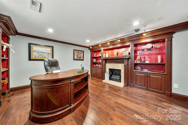 office with crown molding, visible vents, dark wood finished floors, and a fireplace with raised hearth