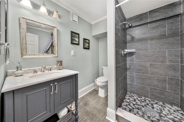 full bath with baseboards, toilet, ornamental molding, a tile shower, and vanity