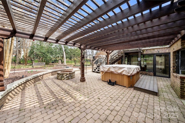 view of patio / terrace with a hot tub, an outdoor fire pit, and fence