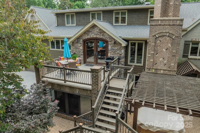 rear view of property with a chimney, roof with shingles, stairs, french doors, and a patio area