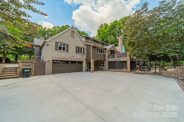 view of front of house featuring a garage, concrete driveway, stone siding, and fence