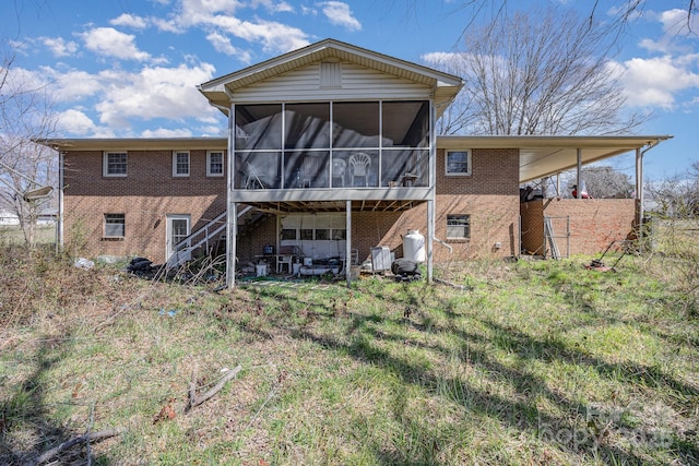 rear view of house featuring a sunroom and brick siding