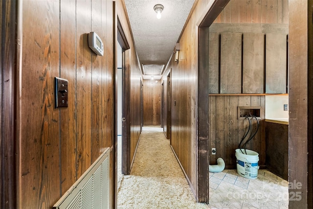 hall featuring a textured ceiling and wood walls