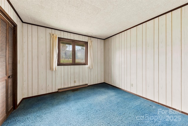 empty room featuring carpet floors, crown molding, a baseboard heating unit, a textured ceiling, and baseboards