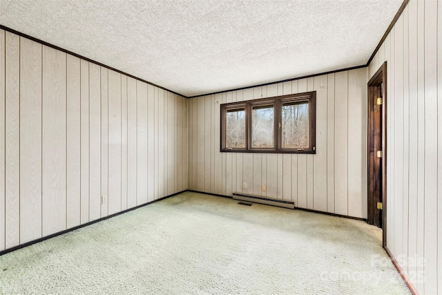 carpeted empty room featuring a textured ceiling, ornamental molding, a baseboard radiator, and baseboards