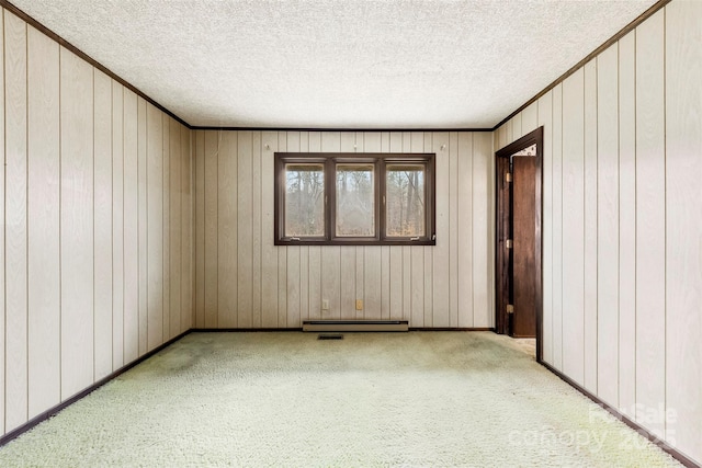 spare room featuring a textured ceiling, carpet floors, baseboards, baseboard heating, and crown molding