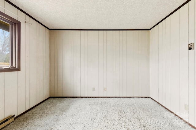 unfurnished room featuring a textured ceiling, a baseboard heating unit, carpet floors, baseboards, and crown molding