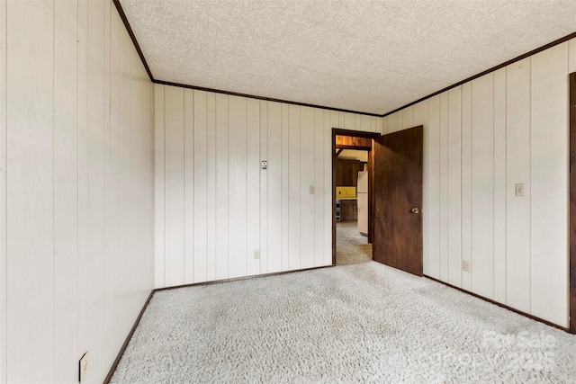 unfurnished bedroom with a textured ceiling, ornamental molding, carpet, and freestanding refrigerator