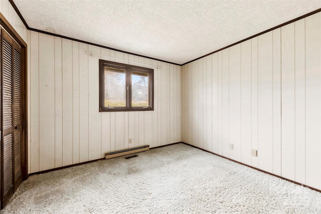 spare room featuring a textured ceiling, carpet floors, a baseboard radiator, and crown molding