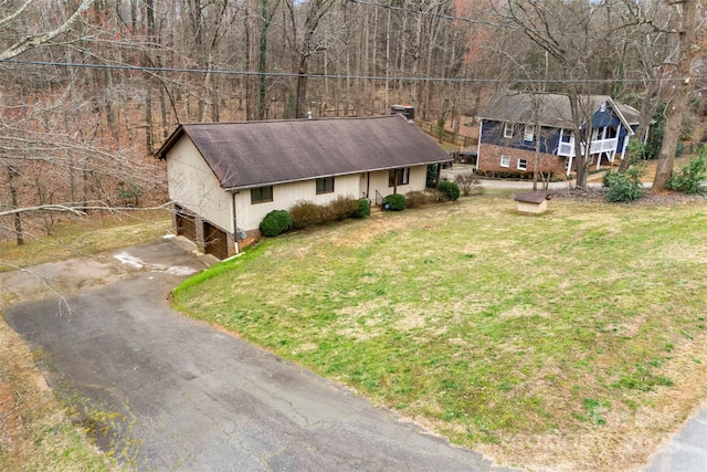 view of front facade with driveway, roof with shingles, and a front yard