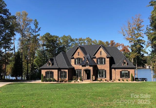 view of front facade featuring a water view, brick siding, and a front yard