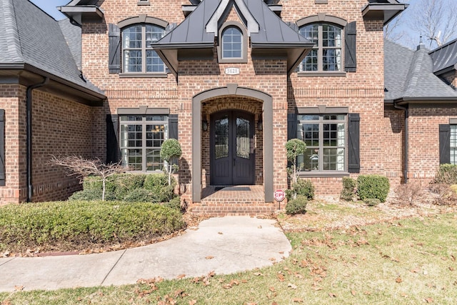 doorway to property featuring french doors, a standing seam roof, a shingled roof, and brick siding