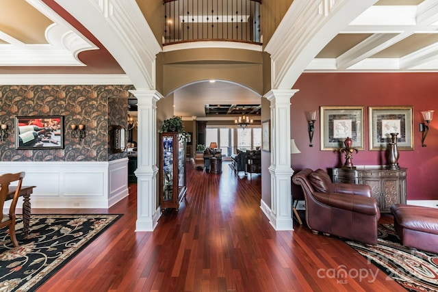 foyer entrance featuring arched walkways, a wainscoted wall, dark wood finished floors, and ornate columns