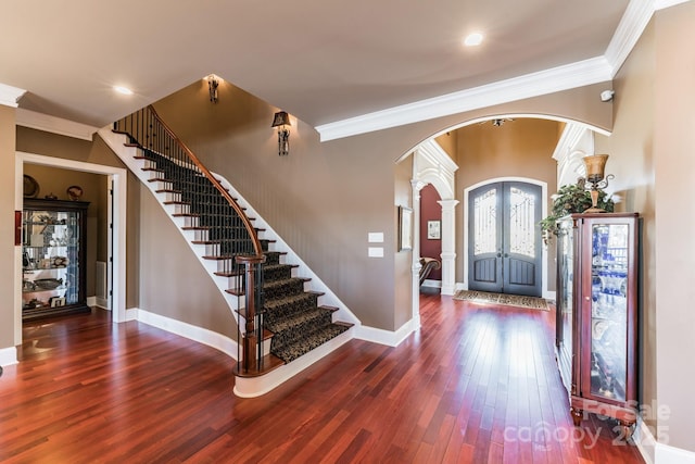 foyer featuring arched walkways, wood-type flooring, and crown molding