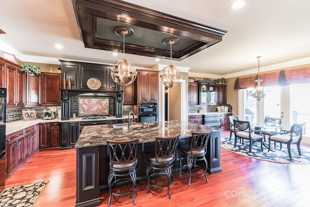 kitchen with crown molding, decorative light fixtures, hardwood / wood-style flooring, and an inviting chandelier