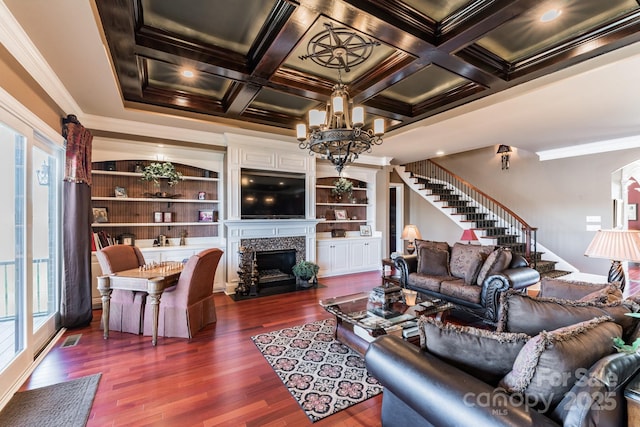 living room with coffered ceiling, a fireplace with flush hearth, stairway, dark wood-style flooring, and a chandelier