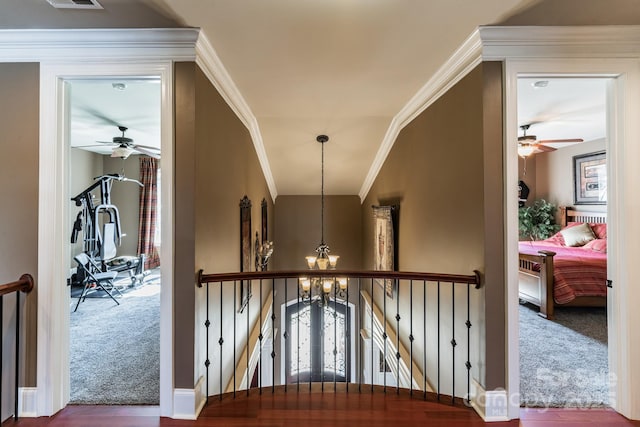 hallway with carpet floors, crown molding, an upstairs landing, and an inviting chandelier