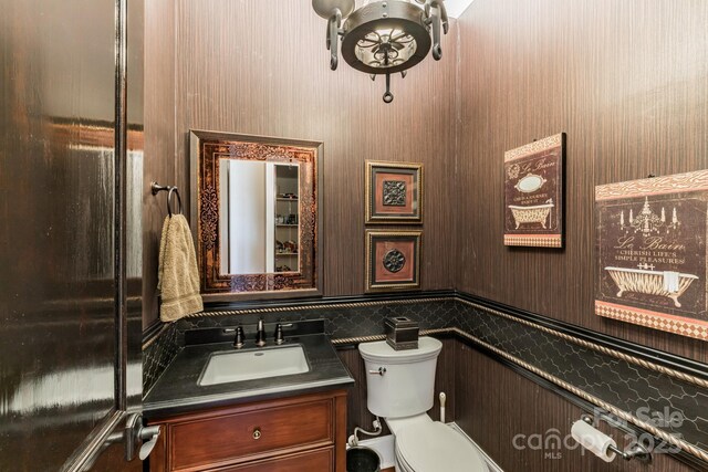 bathroom with toilet, a wainscoted wall, and vanity